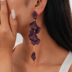 Close-up of matte purple petal tassel earrings on model with golden chain accents