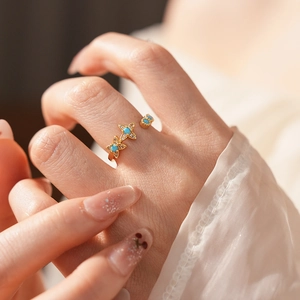 Détail d'une bague ajustable dorée ornée de papillons en turquoise et zircons brillants
