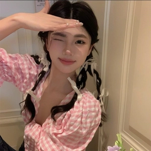 Detailed texture of pink and white plaid fabric on a puff sleeve V-neck blouse