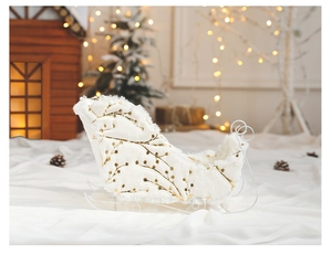 Detail of white plush reindeer sleigh decor with gold dots and metal frame for Christmas