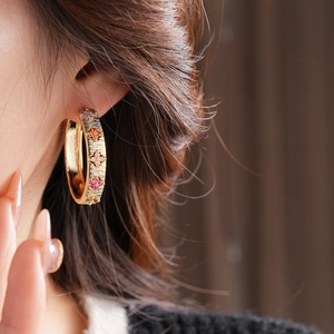 Gros plan de boucles d'oreilles créoles fleurs dorées 18K avec zircons colorés