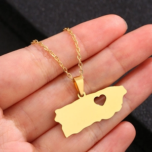 Gold Puerto Rico map necklace with heart cutout held in hand on black background