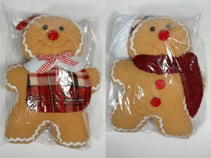 Detail of gingerbread man plush doll in plastic packaging with red scarf and apron