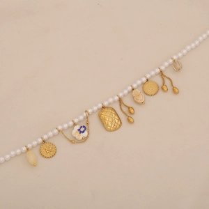 Detailed macro view of baroque pearl necklace with vintage gold heart and sun pendants