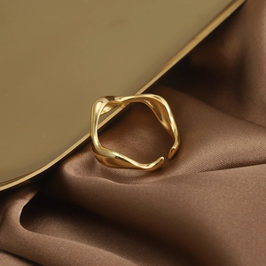 Macro shot of minimalist gold irregular wave ring on elegant brown satin fabric