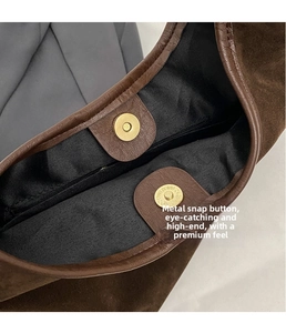Detail of brown suede tote bag featuring a gold magnetic closure and interior zip pocket