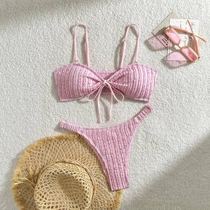 Rosa strukturierter Bikini mit Schleife auf Plüschteppich und Sommer-Accessoires