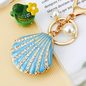 Detailed view of a gold-toned shell keychain with blue stones and pearls on a desk
