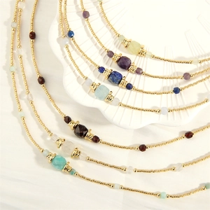 Detail of colorful lapis lazuli and amazonite beaded necklace on white fabric