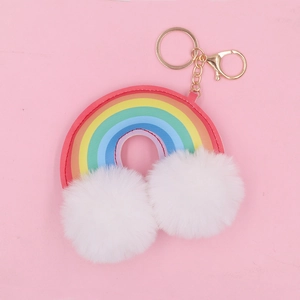 Detailed view of rainbow arch keychain with plush white pom-poms and gold hardware