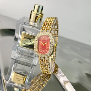 Detail of luxury gold oval watch with red dial and crystal-encrusted hollow bracelet