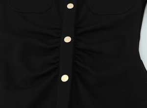 Détail du tissu crêpe noir avec boutons ronds dorés et design plissé élégant