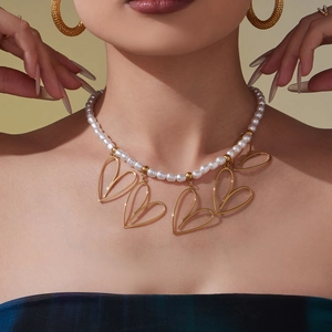 Elegante collana di perle con cinque pendenti a cuore dorati indossata da una modella