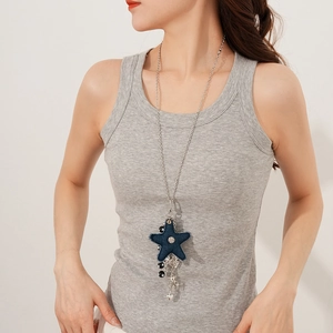 Detail of blue denim star pendant necklace with silver chains and charms on a model