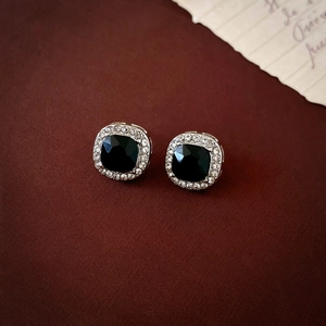 Macro shot of silver square stud earrings with black gemstone and white crystal halo