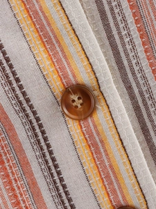 Detail of striped vest with colorful linen texture and brown resin button closure