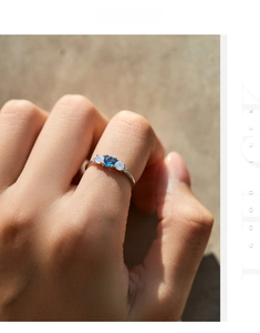 Close-up of s925 silver ring featuring blue center stone and two side opals on a hand