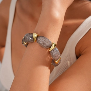 Detail of acrylic oval beads with gold metal connectors on a woman's wrist
