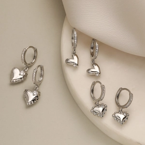 Detailed view of silver heart earrings with sparkling cubic zirconia on a ceramic tray