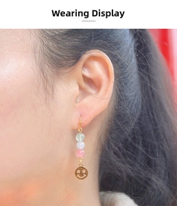 Macro shot of ethnic style drop earrings with three colored beads and a gold smiley pendant