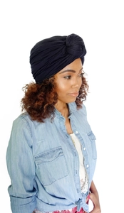 Detail of dark blue pleated turban hat with knotted wrap design worn by a model