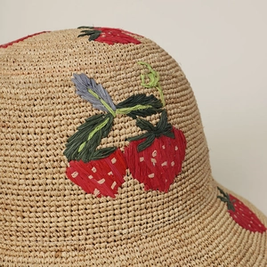 Handcrafted straw hat featuring detailed 3D strawberry embroidery and raffia texture