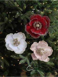 Detail of red, white and pink fabric Christmas flowers with glitter on tree