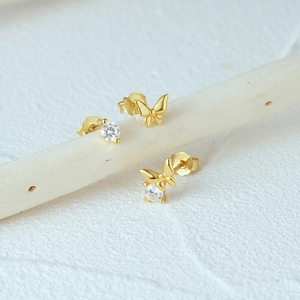 Macro shot of 925 silver gold butterfly and cubic zirconia stud earrings set on a branch
