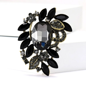 Close-up of elegant black and gold floral brooch with marquise stones and crystal leaf detail