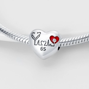 Detailed macro of heart-shaped silver charm with red stethoscope and medical motifs