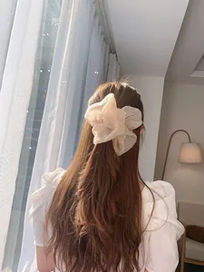 Detail of oversized organza scrunchie in beige showing soft translucent fabric texture