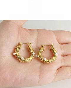 Close-up of 18k gold-plated irregular C-shape hoop earrings with white pearls and crystals