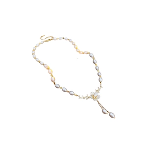 Collier fleur plaqué or avec perles blanches et grises sur fond blanc épuré