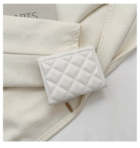 Close-up of white quilted faux leather wallet with classic rhombus pattern on linen fabric
