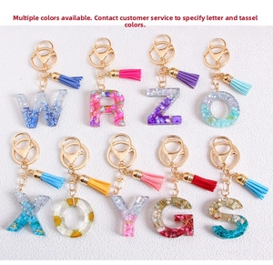 Detail showing various glitter resin alphabet keychains with leather tassels and gold clips