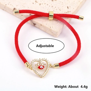 Adjustable red braided rope bracelet with gold heart and evil eye charm weighing 4.4g
