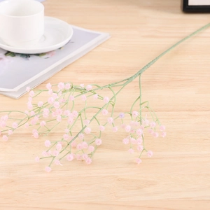 Close-up of pink artificial gypsophila bundle on a light wooden background