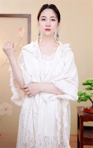 Gros plan sur un châle blanc à capuche en tricot avec des détails de franges de style bohème