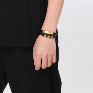 Detail of men's layered leather bracelets with gold metal bar and beaded strands