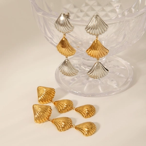 Macro detail of shell-shaped stainless steel drop earrings with fine textured surfaces