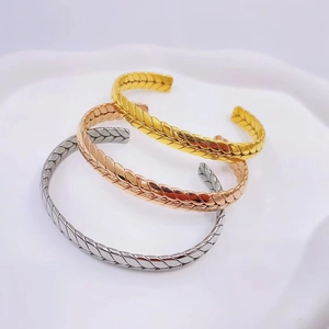 Detailed view of stackable wheat grain texture open bracelets in gold, silver and rose gold
