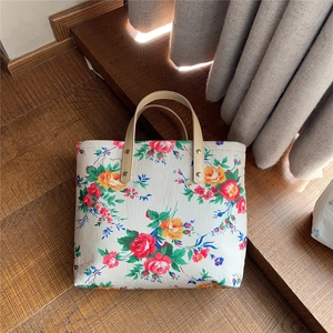 Detail of floral canvas tote bag showing vintage rose print and faux leather handle