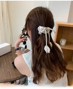 Detail of tulip bow hair scrunchie with long ribbons in black and cream fabric