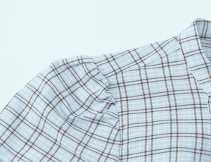 Detail view showing professional shoulder seams and pleated sleeve stitching on plaid dress