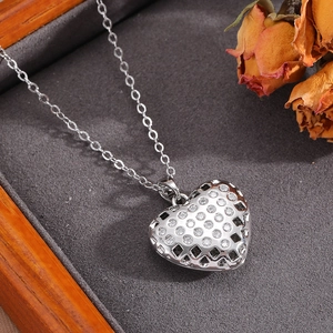 Dettaglio ravvicinato del ciondolo a cuore in metallo argento con zirconi bianchi e trafori