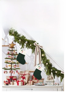 Détail d'une chaussette de Noël en tricot vert avec broderie alphabet rouge sur cheminée