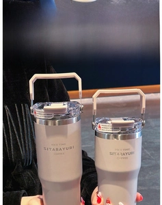 Close-up of insulated stainless steel tumbler with folding handle and straw lid