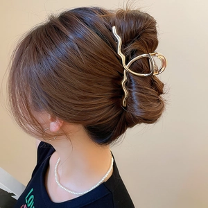 Close-up of golden wavy metal hair claw clip holding hair in a stylish half-up hairstyle