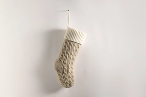 Close-up of beige cable knit Christmas stocking with white ribbed cuff on white background