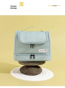 Detail view of a dual-layer light green toiletry bag with high-quality metal zippers